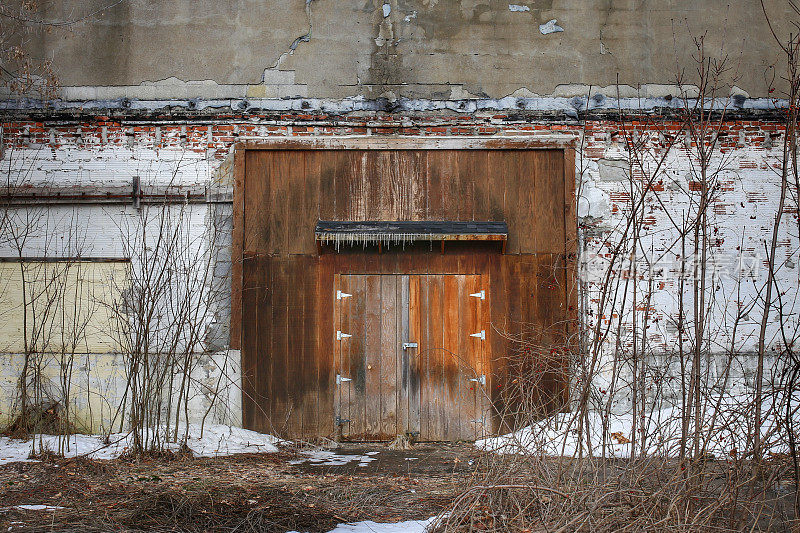 乡村老工业建筑大木门，雪，杂草
