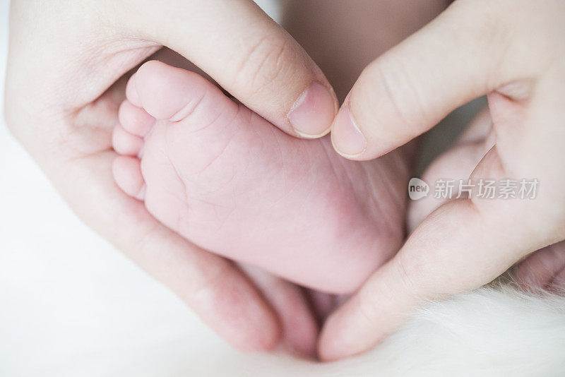 亚洲母亲的手和婴儿的脚