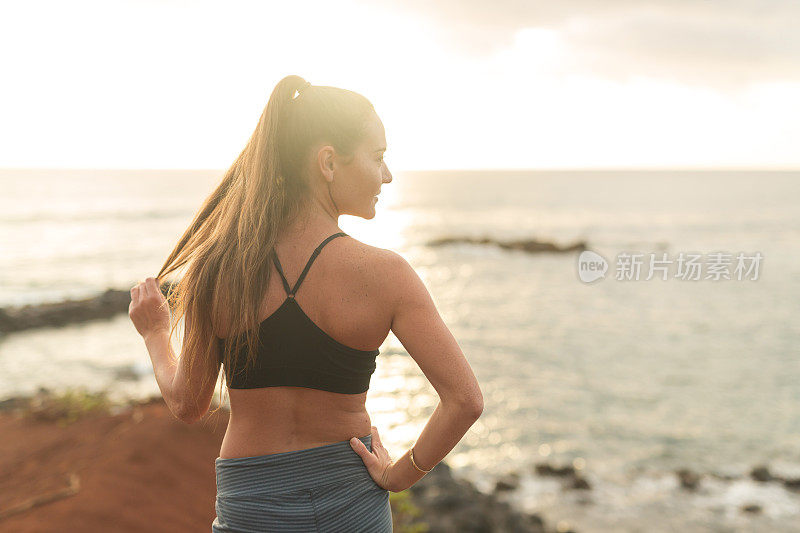 年轻的欧亚混血女子在夏威夷海岸线跑步后休息