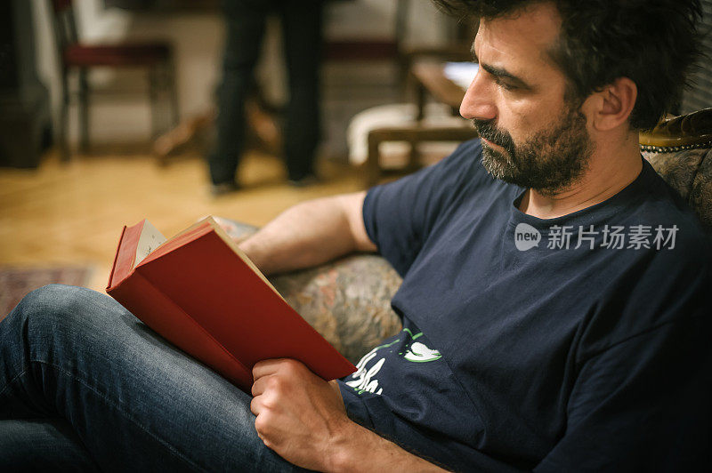 一个男人坐在家里的老式椅子上看书