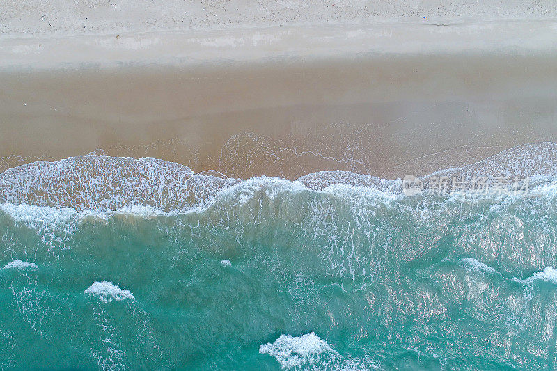 海滩上无人机俯视图海浪到达海岸。