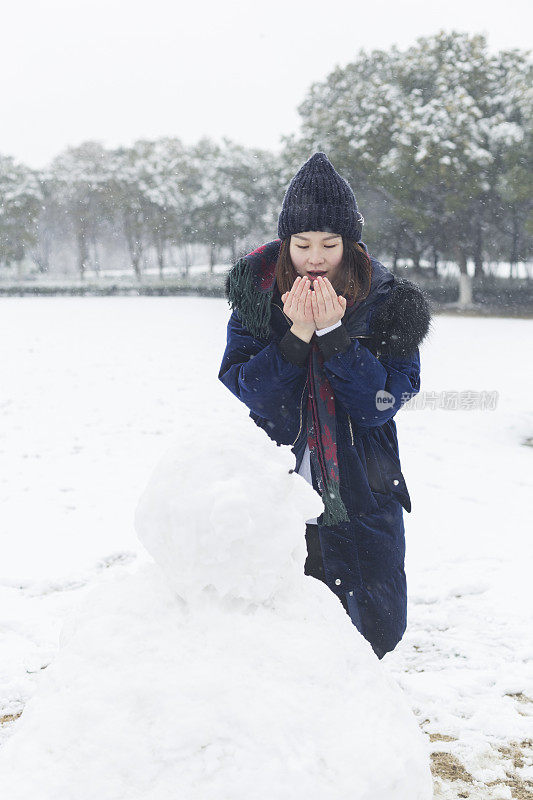 一个女人在堆完雪人后暖手