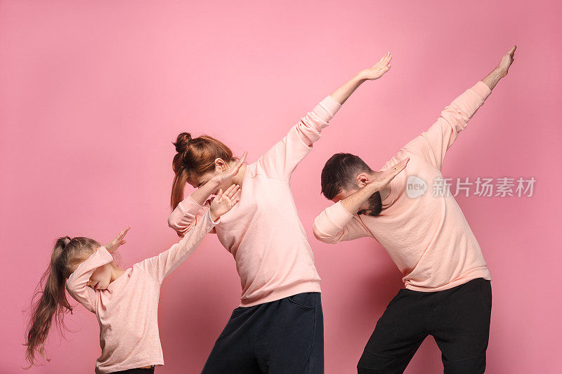 跳舞的年轻的家庭在粉红色