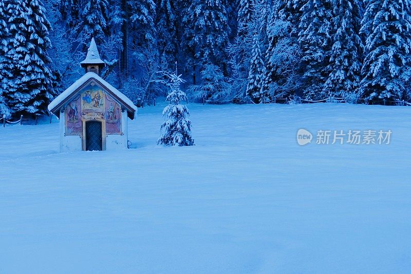 白雪覆盖的景色中的小教堂和圣诞树