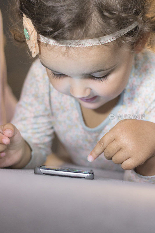 小女孩用智能手机在网上看卡通。