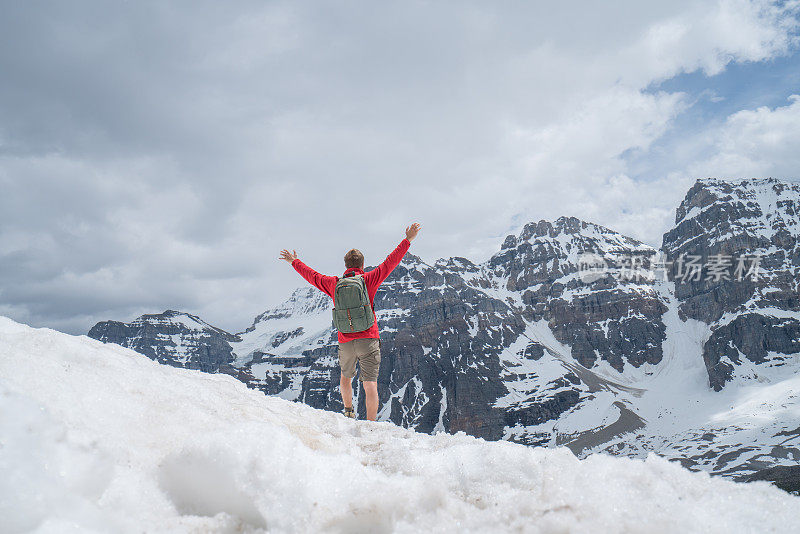 年轻人在雪道上徒步旅行，双臂张开