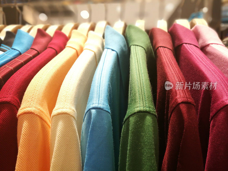 不同颜色的男式衬衫挂在零售服装店的衣架上