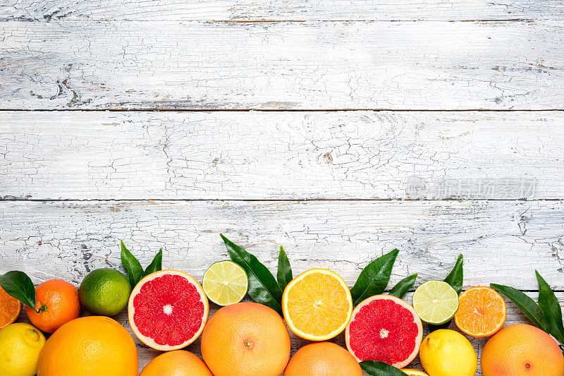 柑橘类水果的背景。水果篮橙，柚子，柠檬，酸橙，橘子在白色的桌子上。什锦新鲜柑橘类水果。俯视图，平放