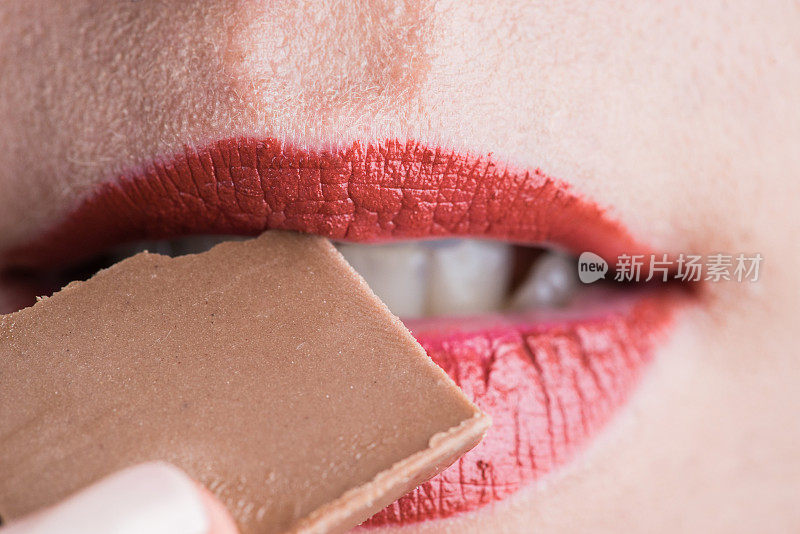 女性嘴唇咬巧克力的微距镜头。