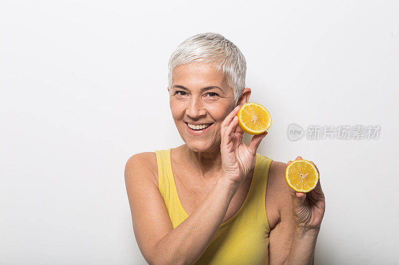 成熟的女人手里拿着柠檬，微笑着