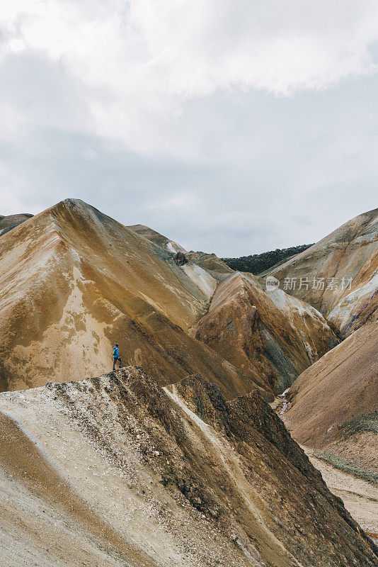 在冰岛的Landmannalaugar，一名妇女在彩色山脉附近徒步旅行