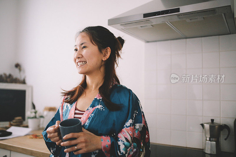 年轻的亚洲女性在家里放松，喝着早茶