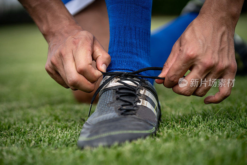 一个足球运动员在足球场上系鞋带的特写镜头