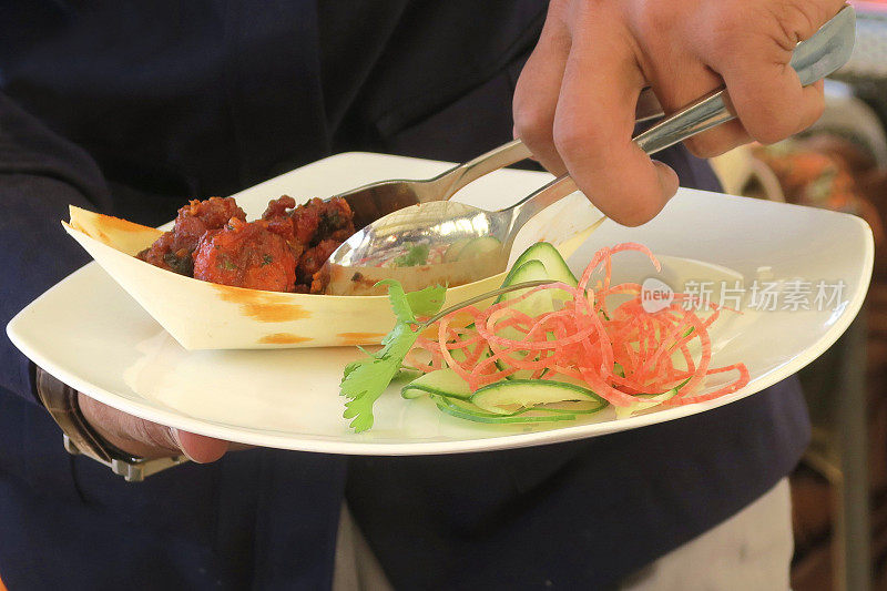 想象一下，在印度餐厅用餐时，服务员用叉子和勺子端上来的食物，辛辣的油炸鸡肉炸丸子食谱，外面的餐桌上有非蔬菜的肉，配上黄瓜、香菜、胡萝卜的印度沙拉，德里，印度