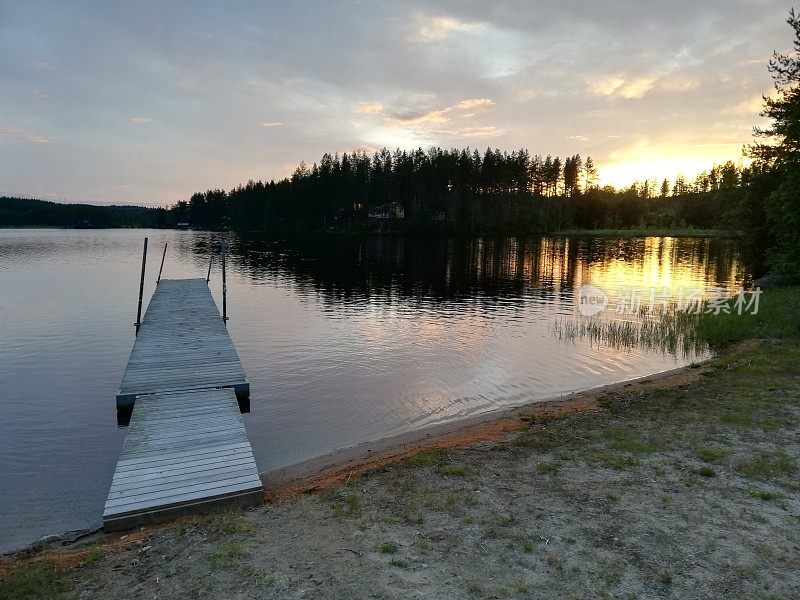 瑞典北部的加夫塞尔json湖和码头，湖面上有夕阳和倒影