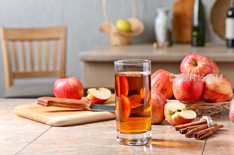厨房桌子上放着一杯苹果汁和熟透的粉红苹果