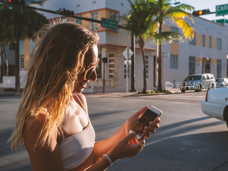 在智能手机上使用拼车应用的年轻女性，在城市街道上使用手机拼车应用的女孩，在线拼车或拼车服务。现代生活中的科技和交通