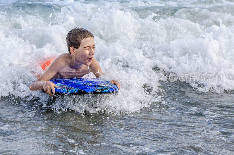 小男孩带着小冲浪板在海滩上