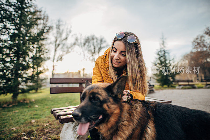 公园里有个年轻女人和一只德国牧羊犬