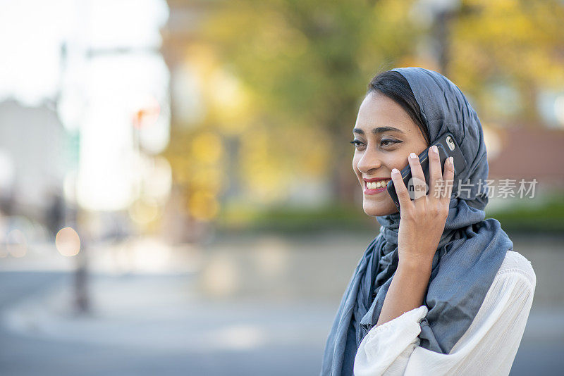 年轻的穆斯林女性在用她的智能手机