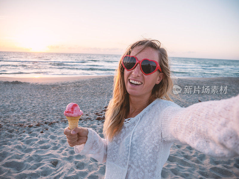 夏日里，快乐的女人在海滩上吃冰淇淋，戴着心形眼镜