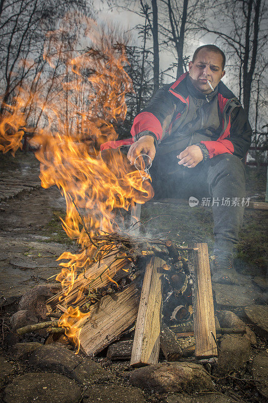 一个男人在火边抽烟。