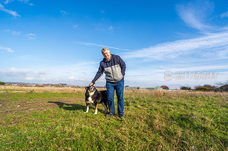 一名男子和边境牧羊犬在草原上散步