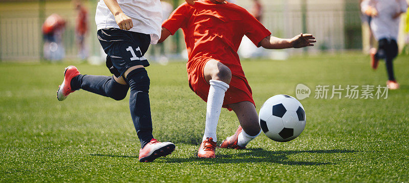 足球运动员决斗跑步。在学校的比赛中，足球运动员在草地上快速奔跑和踢足球。足球后卫和前锋之间的比赛