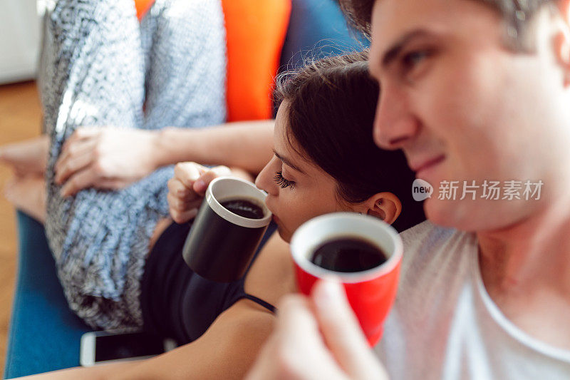 年轻夫妇正在喝咖啡，舒服地躺在沙发上