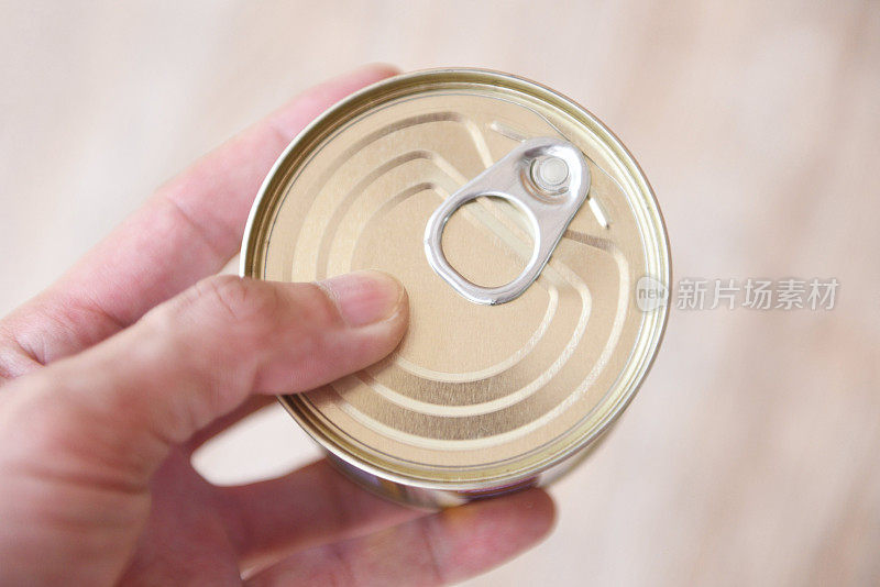 罐头食品金属易拉罐在手，罐头食品不易腐坏，食品储存在厨房，家庭或捐赠