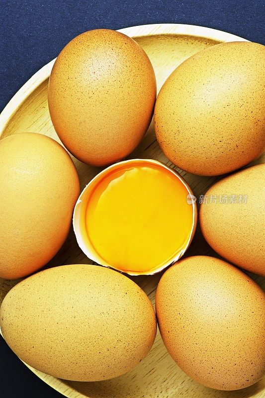 鸡蛋和蛋黄放在圆形木托盘上。