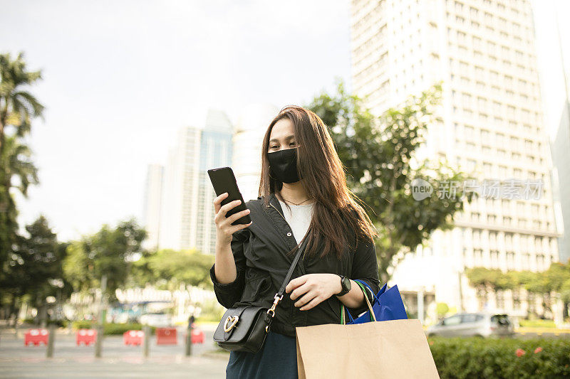 亚洲女性在街上走路时使用手机