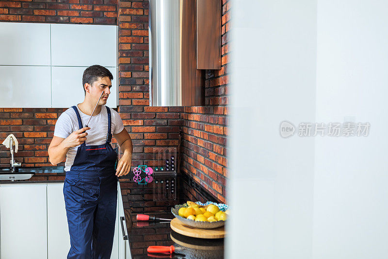 男电工带着夹板修理厨房抽油器过滤器