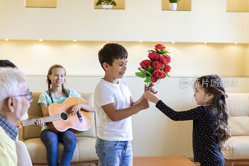 一个小男孩送给他可爱的妹妹一朵红玫瑰作为生日礼物。