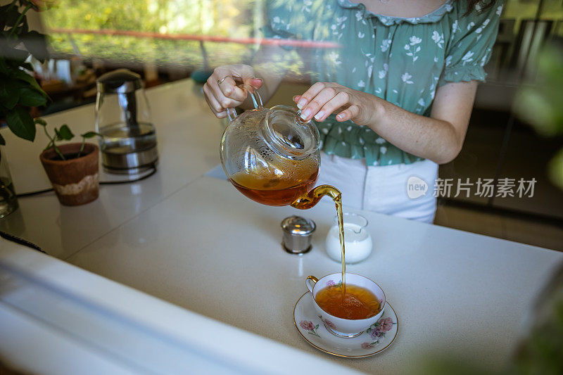 年轻女子正在准备一壶散装茶叶。