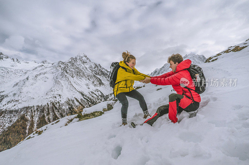 一对年轻的徒步旅行者在白雪皑皑的山脊上嬉戏