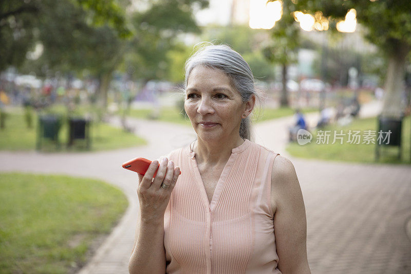 老女人在公园外面玩，玩智能手机