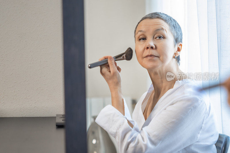 成熟的女人会在镜子前用化妆刷化妆