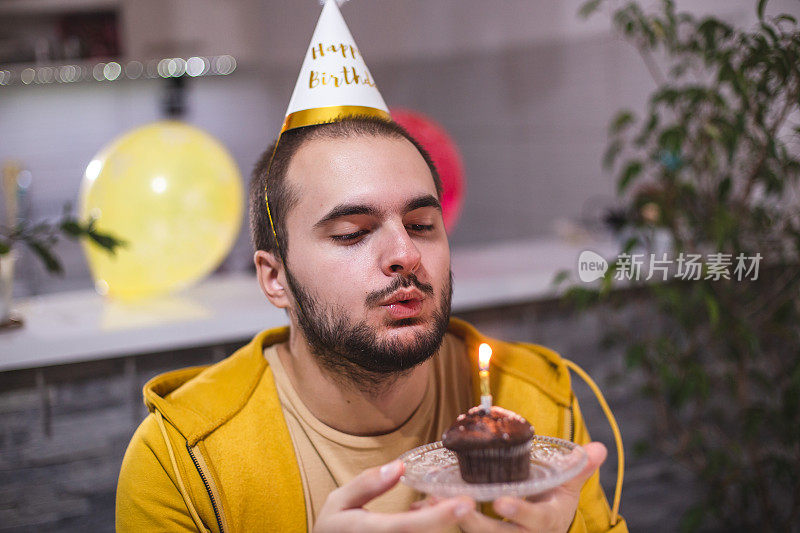 一名年轻人在COVID-19冠状病毒大流行期间与朋友视频通话庆祝生日，吹蜡烛