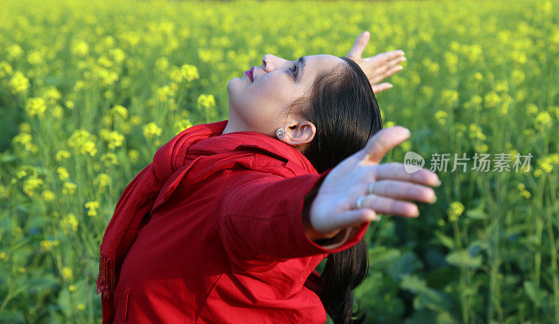 在春天，漂亮的女人站在芥末田里的肖像