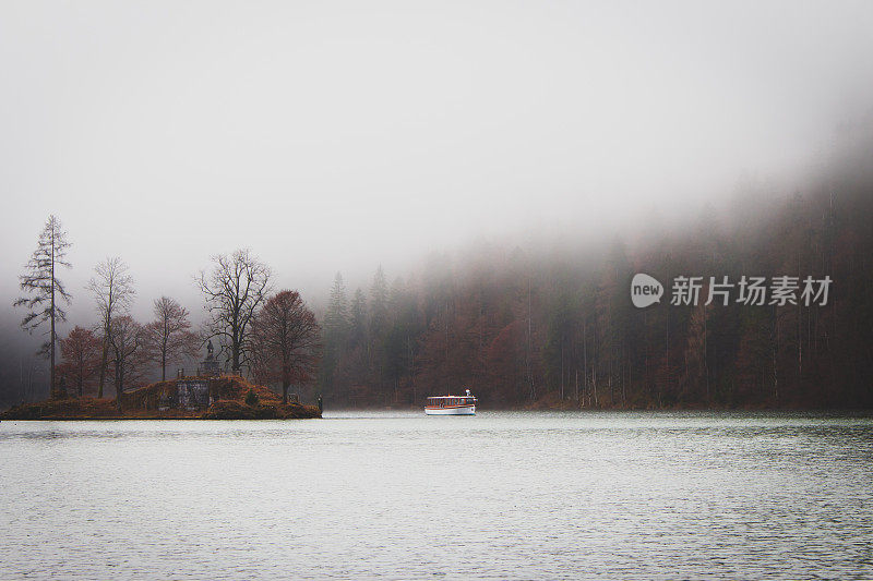 德国肯尼格湖上的雾。湖中央有小岛和游船。雾在湖岸上。德国的风景。秋景在欧洲贝希特斯加登国家公园。