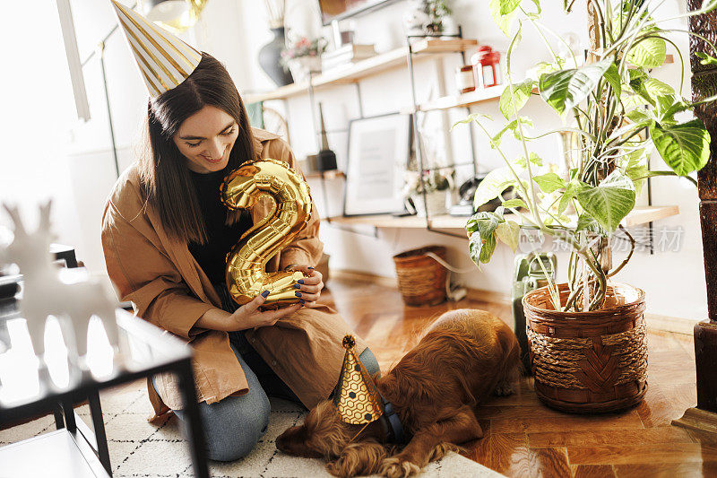 一位年轻女子在家里和她的狗狗一起庆祝她的狗狗生日。