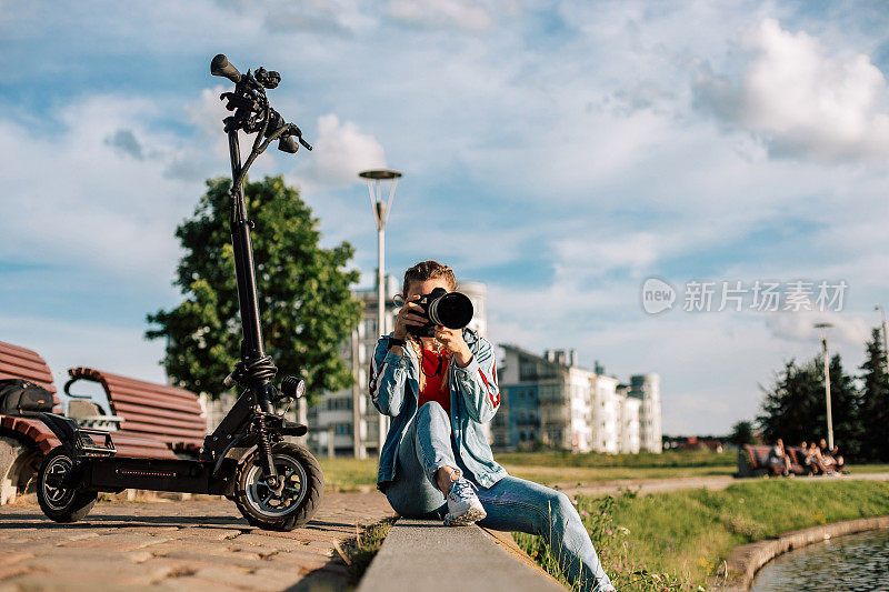 女人是专业摄影师。有人在电动滑板车附近拍照。女士在城市公园工作。女人的肖像谁使用电动踢踏板车。
