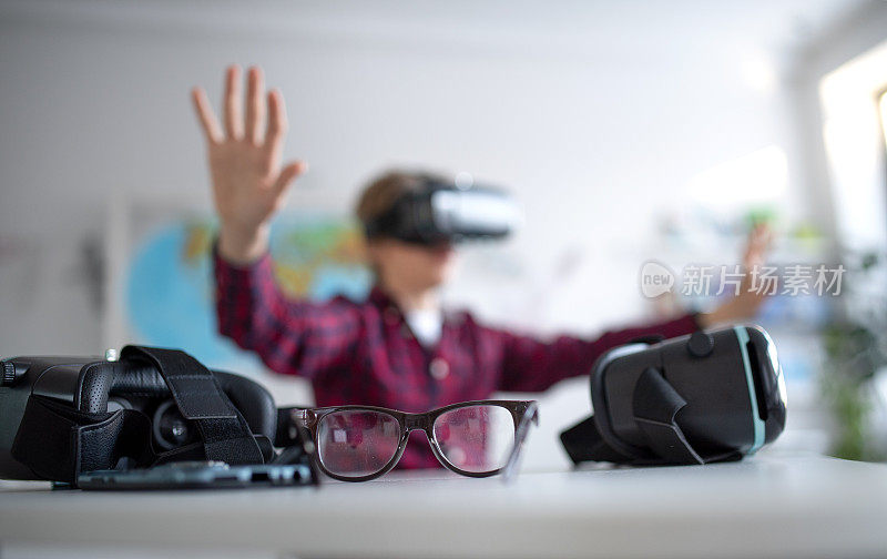 快乐的学生戴着虚拟现实眼镜在学校的计算机科学课上，近距离观察眼镜。