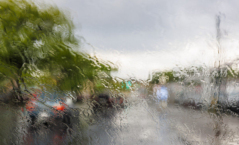 在倾盆大雨中行驶在纽约皇后大道上。从驾驶室看到的挡风玻璃上的风景。街道因为水的影响而变得模糊和扭曲。