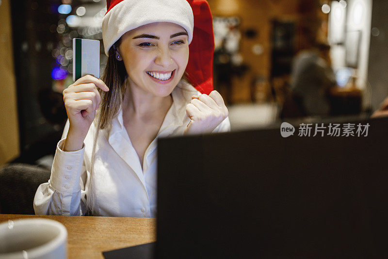 圣诞购物。微笑的女士使用笔记本电脑显示信用卡