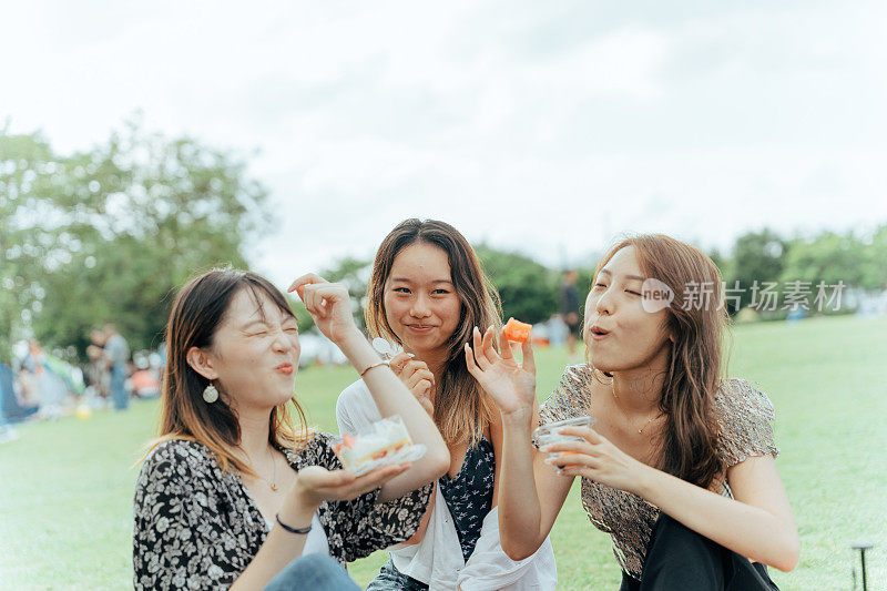 三个年轻的亚洲女性朋友一起在公园野餐，吃蛋糕