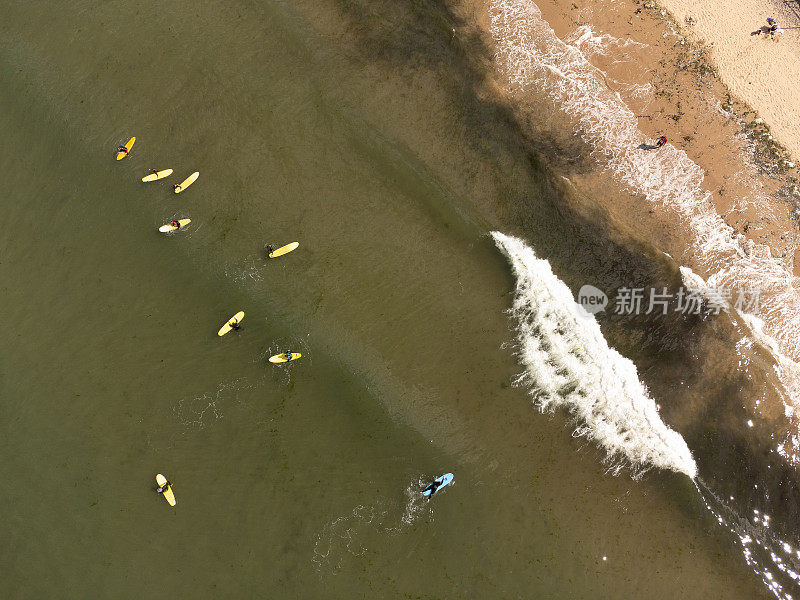 英国北约克郡萨尔特本的空中海岸线场景，冲浪者在平静的北海上。用0级无人机拍摄的