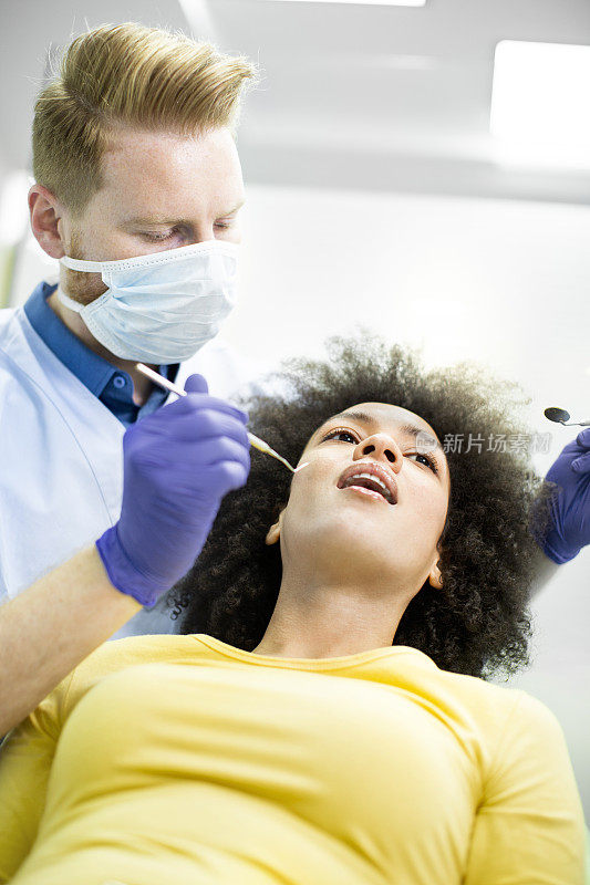 牙医使用挖掘机镰刀探针和口镜进行牙科检查