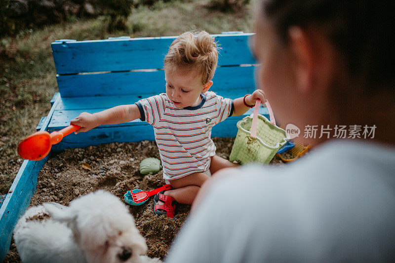 孩子和他的单身母亲在沙盒里玩耍